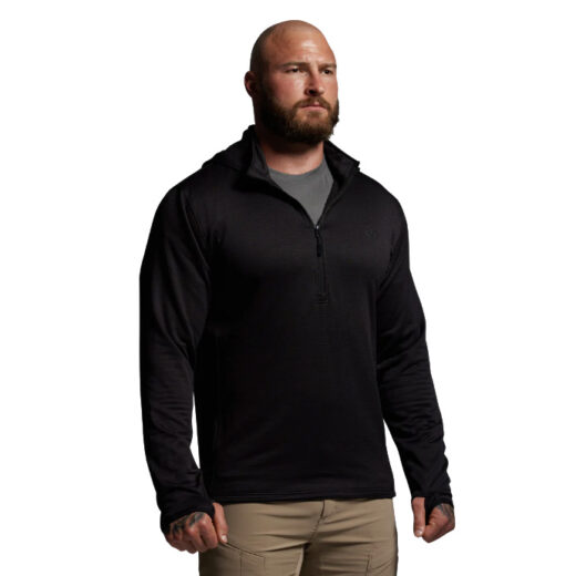 Men’s Ridgeline Half Zip Hoodie – Black The Ridgeline Half Zip Hoodie is built to be the cornerstone of your cold-weather layering system, offering premium performance from a lightweight, next-to-skin design. Crafted from a super-soft Merino wool blend, it delivers the perfect balance of warmth, moisture management, and comfort for extended use in the field. Merino’s natural properties make it one of the most versatile fibers available to hunters and outdoorsmen. It’s highly breathable, quick-drying, and antimicrobial, meaning it resists odor even after days of hard use. Unlike synthetic fabrics, Merino maintains its insulation value even when wet, keeping you warm and dry no matter how demanding the conditions. Combined with the added durability of synthetic fibers, this hoodie stands up to rugged use season after season. The half-zip design allows for easy temperature regulation—zip it up when the cold sets in or vent it quickly during strenuous climbs. A streamlined hood adds another layer of protection against wind and cold without excess bulk, making it ideal under mid and outer layers. Flatlock seams minimize chafing, while the athletic cut ensures unrestricted mobility, whether you’re glassing ridgelines, hiking deep into backcountry terrain, or sitting through long, frigid sits. Key Features: Merino Wool Blend – Soft, breathable, and naturally odor-resistant. Moisture-Wicking & Quick-Drying – Stays dry and comfortable during exertion. Half-Zip Venting – Allows quick heat release and easy layering. Streamlined Hood – Provides added warmth and coverage without bulk. Next-to-Skin Fit – Optimized for layering efficiency. Recommended Conditions: Cold to Frigid when paired with a mid layer and/or outer layer. Whether worn as a foundation piece or integrated into a full layering system, the Men’s Ridgeline Half Zip Hoodie is a must-have for serious hunters and adventurers facing unpredictable conditions.